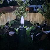 Dominicans praying to Rosary at night around a statue of Mary, the Mother of Mercy in the garden